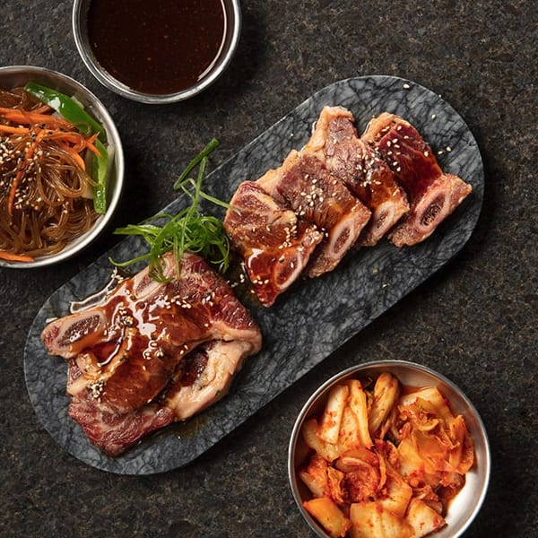 Marinated Korean short ribs with sesame seeds, glass noodles, kimchi, and dipping sauce.